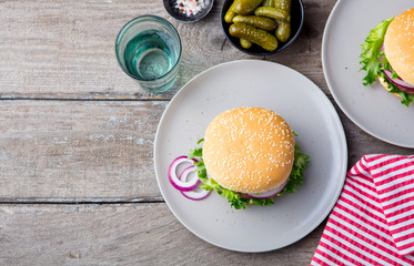 Burger on a plate with pickles. Wooden background. Copy space.