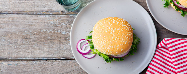 Burger on a plate with pickles. Wooden background. Copy space.