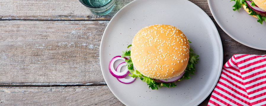 Burger on a plate with pickles. Wooden background. Copy space.