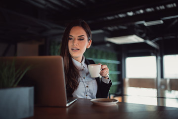 Young businesswoman looking at her laptop while having a coffee break