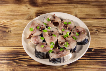 Sliced mackerel with spices on wooden table. Salted scomber on a plate