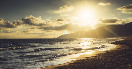 Sunlight sunset on horizon ocean on background seascape atmosphere rays sunrise. Relax view waves sea with kitesurfing on sand beach,  sun light flare nature evening concept, copy space for text.