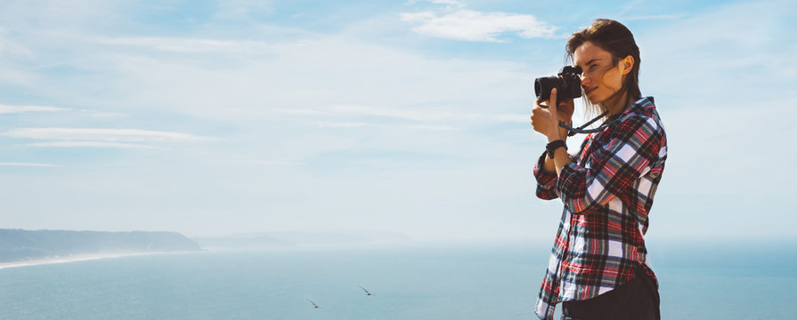Tourist traveler photographer making pictures sea scape on photo camera on background ocean, hipster girl looking on nature horizon, relax holiday, blank space blue waves view, blurred backdrop