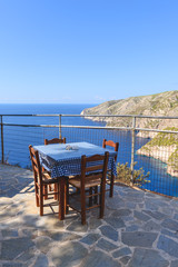 Fototapeta premium Tables with chairs on terrace of coastal restaurant in Porto Schiza on Zakynthos island. Greece.