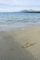 Footprints in the sand of a beach by the Mediterranean sea on the island of Ibiza in Spain, holiday and summer scene