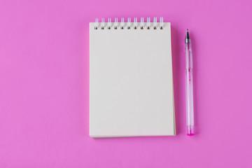 Notebook and pen on pink background. Space for text