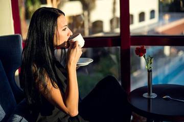 Portrait of beautiful young woman sitting at a table with a cup of coffee