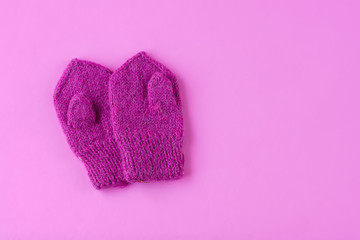 Children's mittens on pink background. Space for text