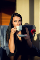 Portrait of beautiful young woman sitting at a table with a cup of coffee