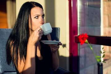 Portrait of beautiful young woman sitting at a table with a cup of coffee
