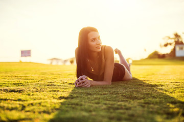 happy beautiful woman in bikini on the green grass on sunset.