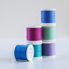 Bobbins of blue, green, purple, violet, lilac thread for sewing. Copy space