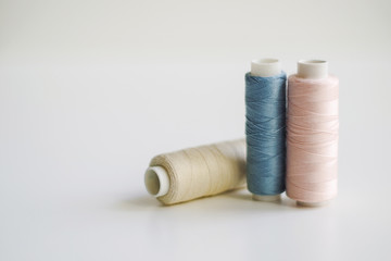 Bobbins of light blue, pink, yellow thread for sewing.  Pastel colors. Copy space