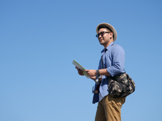 Naklejka premium Asian man travel with map and vintage camera on blue sky background