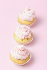 Cupcake decorated with pink buttercream on pastel pink background. Sweet beautiful cake. Vertical banner, greeting card for birthday, wedding, women's day. Close up photography. Selective focus