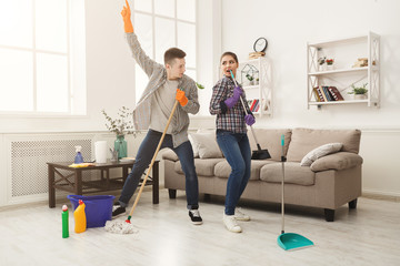 Young couple cleaning home, playing with mop
