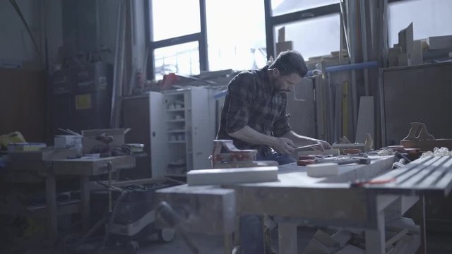 Handsome man in his fourties working with wood in his workshop