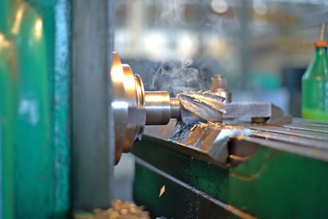 The detail is clamped by clips on a table. Dry boring by a trailer mill with a smoke and steam. milling machines industrial metalworking cutting process by milling cutter cutting