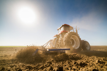 Farmer in tractor preparing land with seedbed cultivator as part of pre seeding activities in early...