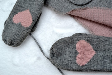 Winter woolen textile. Scarf and mittens on the snow. Beautiful winter background. Cold season.
