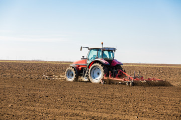 Farmer in tractor preparing land with seedbed cultivator as part of pre seeding activities in early spring season of agricultural works at farmlands.