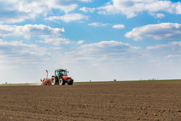 Obraz premium Farmer seeding, sowing crops at field. Sowing is the process of planting seeds in the ground as part of the early spring time agricultural activities.