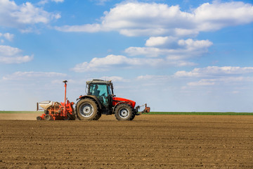 Obraz premium Farmer seeding, sowing crops at field. Sowing is the process of planting seeds in the ground as part of the early spring time agricultural activities.