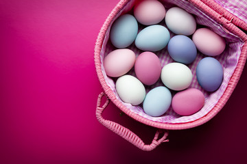 Easter background - colored eggs in basket on pink background