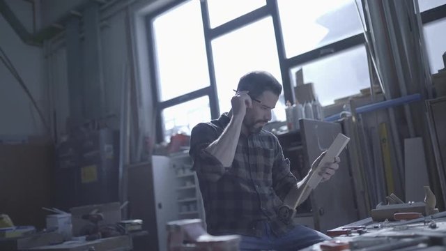 Handsome man in his fourties working with tools and wood at his workplace