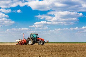 Obraz premium Farmer seeding, sowing crops at field. Sowing is the process of planting seeds in the ground as part of the early spring time agricultural activities.