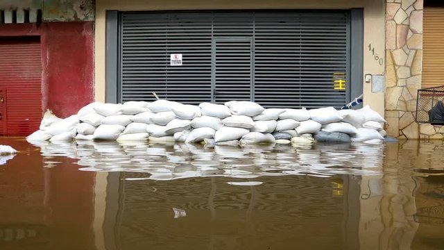 Establishing shot of a building with a sandbag barrier surrounded by flood water