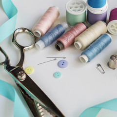 Spools of thread and basic sewing tools including pins, needle, a thimble, and tape measure. Copy...