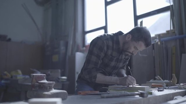Handsome man in his fourties working with tools and wood at his workplace