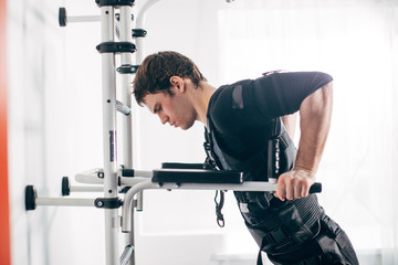 EMS male working out, doing push ups. Fit man doing triceps dips on parallel bars