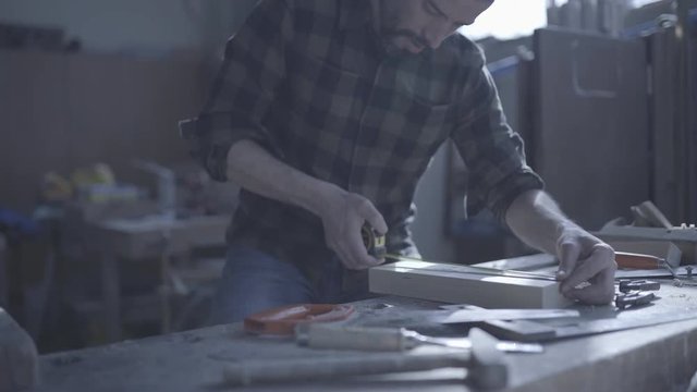 Handsome man in his fourties working with tools and wood at his workplace