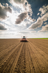 Farmer seeding, sowing crops at field. Sowing is the process of planting seeds in the ground as part of the early spring time agricultural activities.