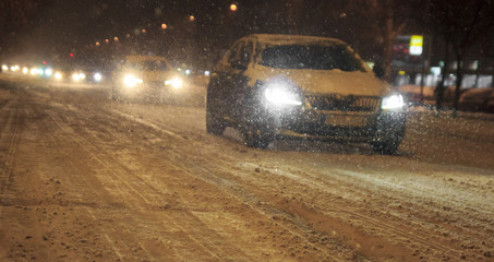 Traffic in the city cars bad weather and snow fall blizzard by night