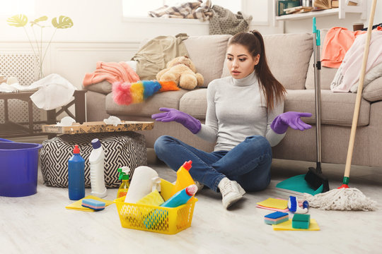 Shocked woman cleaning house with lots of tools