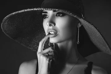 schönes Porträt eines Mädchens mit Hut auf schwarzem Hintergrund, Schwarz-Weiß-Foto © Екатерина Переславце