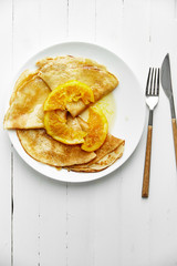 Overhead image of pancakes with orange confiture in white plate on wooden table