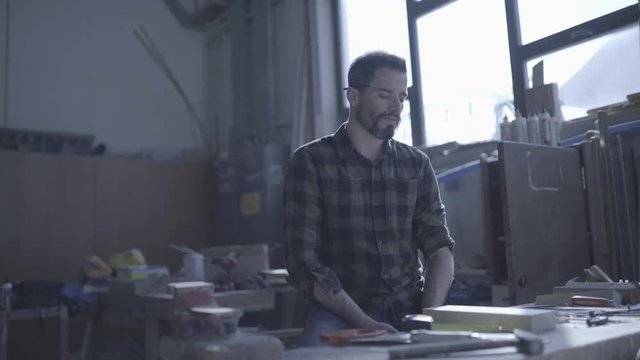 Handsome man in his fourties working with tools and wood at his workplace