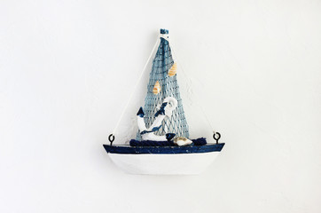 Small toy boat on white concrete background top view, white and blue simple colors. Inspirational marine traveling decor. 