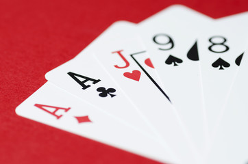 Playing cards on red background close up, soft focus
