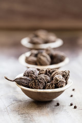 Black cardamom in a bowl on wooden background