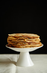 Crepes cake with orange jam and honey on white cake stand. Pancake breakfast concept