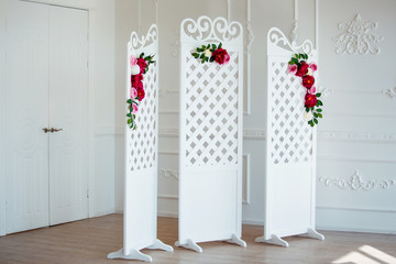 White delicate decorative wood panel in classical interior. Boudoir wedding room. Retro folding screen with flowers. Vintage ornate carved folding screen.