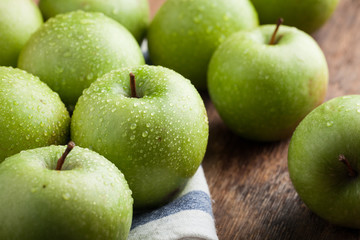 Ripe green apples in a wooden bowl on an old rustic table. Useful fruits on wooden background. Top view