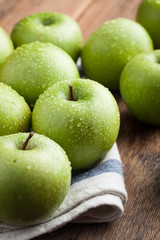 Ripe green apples in a wooden bowl on an old rustic table. Useful fruits on wooden background. Top view