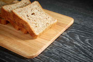 Fototapeta na wymiar Sliced bread on wooden cutting Board, on dark wooden background, bran
