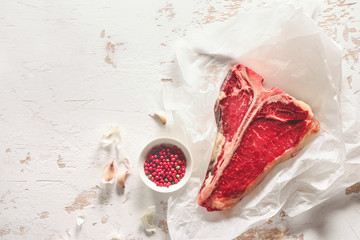 T-bone raw steak on a kitchen table surface, view from above